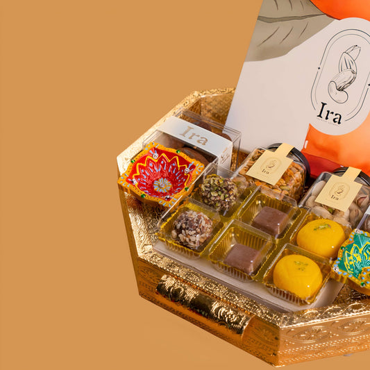 Assorted small containers of snacks in a decorative box with 'Ira' Diwali Ramadan& Christmas gift box