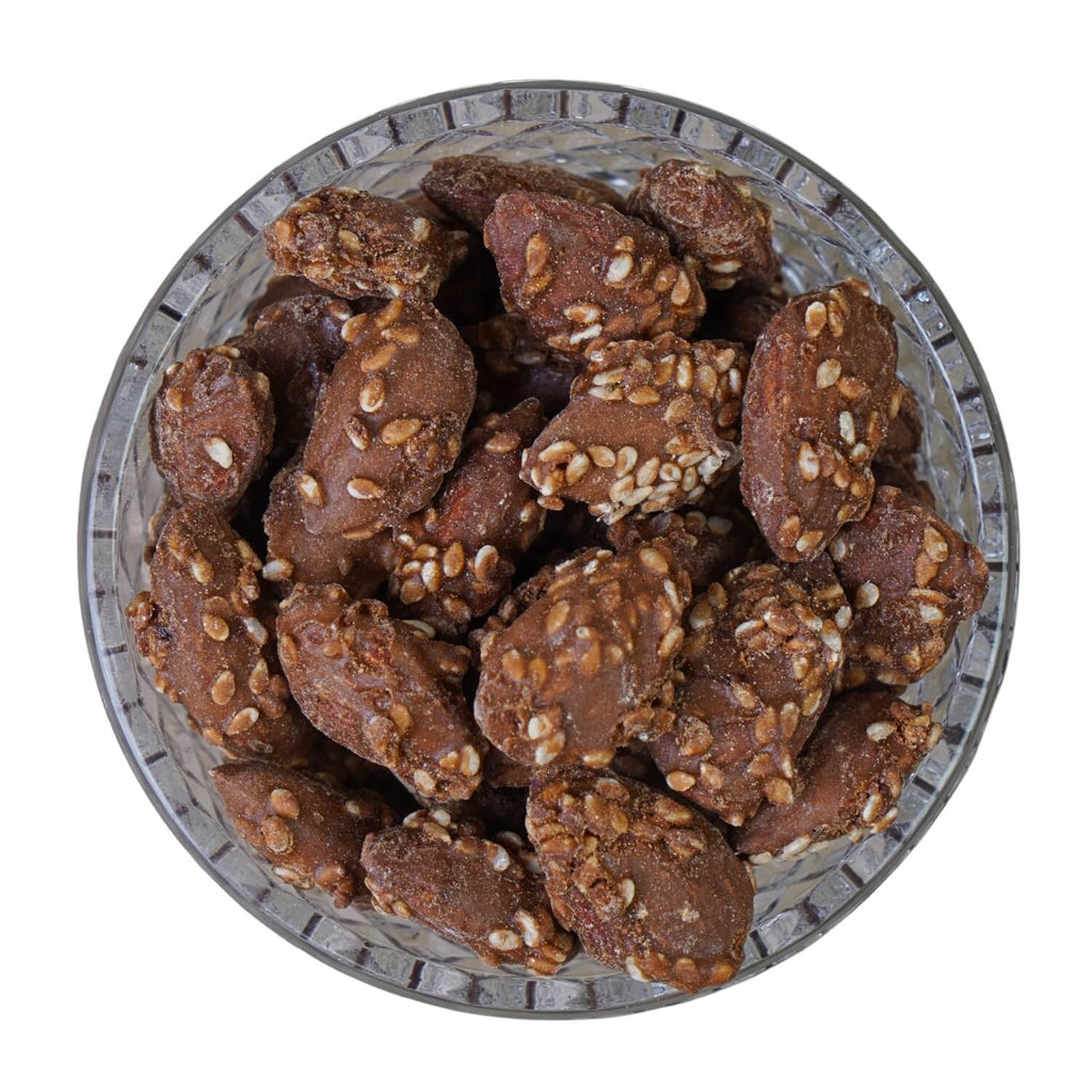 Glass bowl filled with chocolate cookies and nuts on a white background