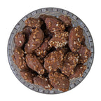 Glass bowl filled with chocolate cookies and nuts on a white background