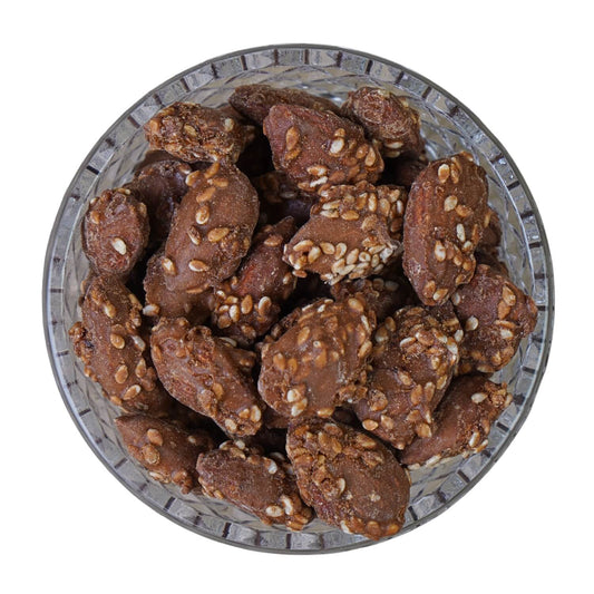 Glass bowl filled with chocolate cookies and nuts on a white background